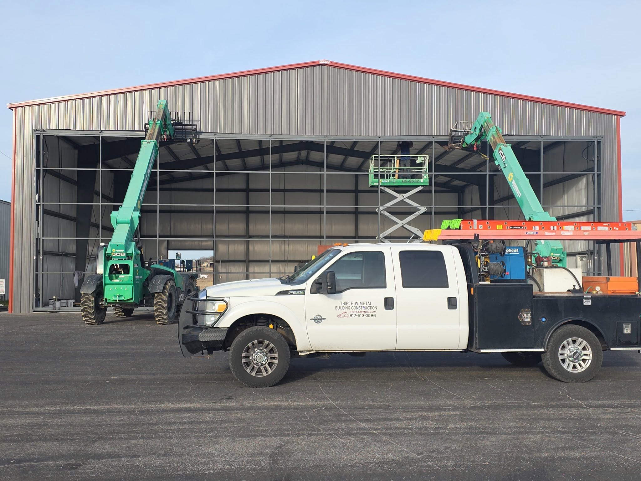Aircraft hangar framing with a Triple W Metal Building Construction work truck on site